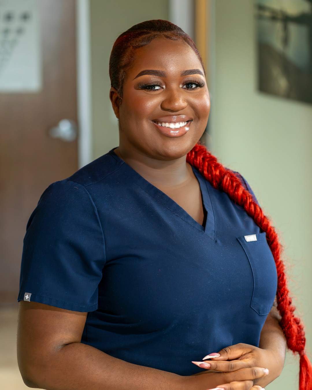 Black woman with red braided hair wearing blue scrubs